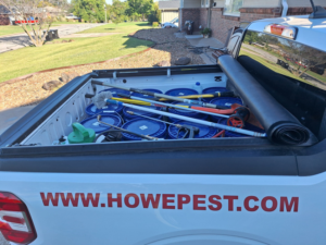 A Howe Pest Management truck in Manhattan, KS, loaded with pest control equipment and blue buckets, ready for service.
