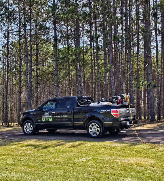 A pest control truck with a hose extended, ready for service by BugMeisters North in Lindstrom, MN
