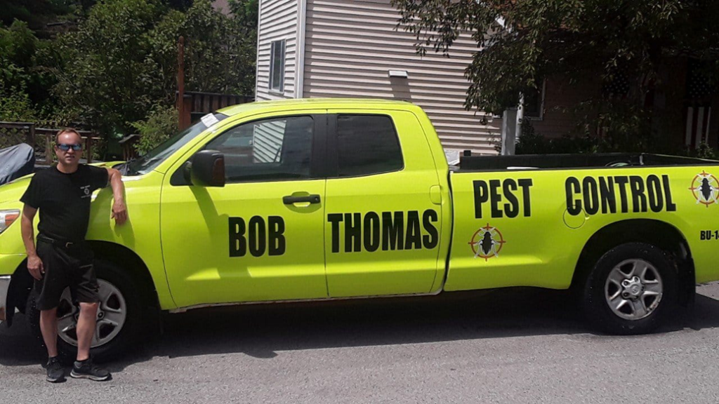 A Bob Thomas Pest Control truck parked in a rural setting under a dark sky in Latrobe, PA.