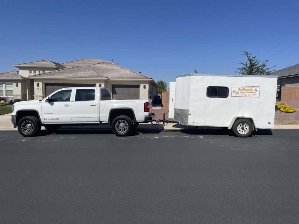 A white pickup truck and trailer ready for a pest control job by Reliable pest control solutions in Hannibal, MO
