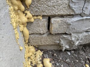 Expanding foam sealant applied to seal gaps in a stone foundation, demonstrating pest exclusion work by Moderno Pest Control in Fort Wayne, IN.