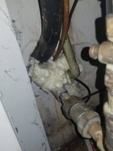 Expanding foam sealant applied around pipes and wires in a utility area for pest exclusion by Corsello & Son Pest Control Services in Atlanta, GA.