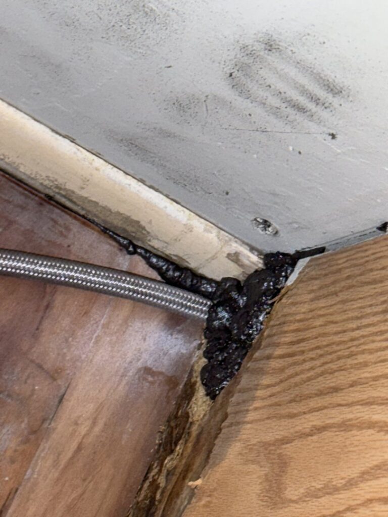 Black sealant applied to a gap for pest exclusion, a service provided by Charm City Pest Control Solutions LLC to prevent pests in Baltimore, MD.