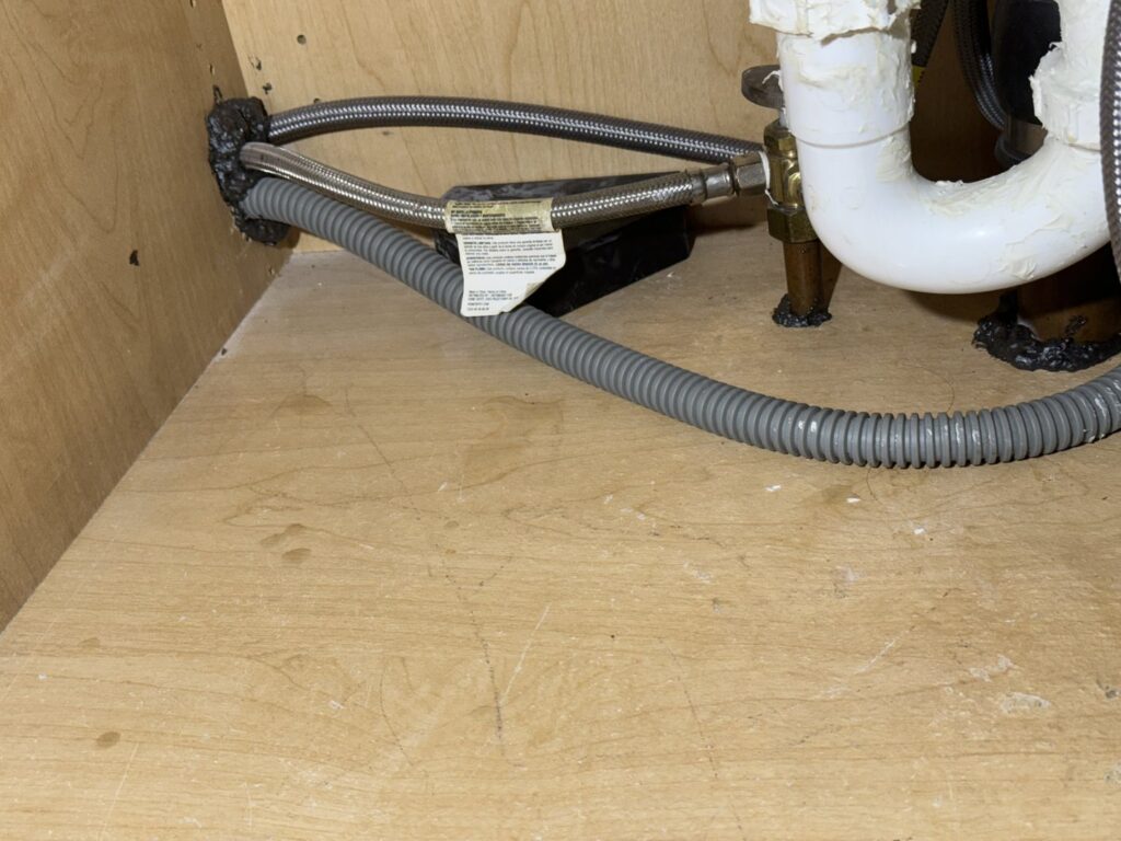 Pest exclusion sealing applied under a kitchen sink to prevent entry, a service from Charm City Pest Control Solutions LLC in Baltimore, MD.