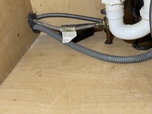 Pest exclusion sealing applied under a kitchen sink to prevent entry, a service from Charm City Pest Control Solutions LLC in Baltimore, MD.
