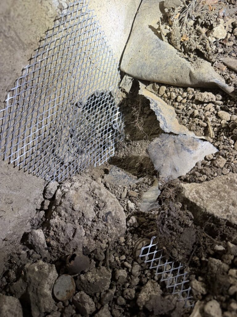 Close-up of wire mesh installed in a rocky area for pest exclusion by Rogue Valley Extermination & Pest Control in Medford, OR.