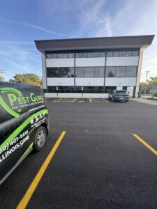 A Pest Guru Illinois branded van parked outside a commercial building for a pest control job in Elgin, IL.