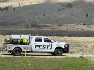 A Pest One service truck with hoses extended, actively performing pest control or plant health treatment in Bozeman, MT.