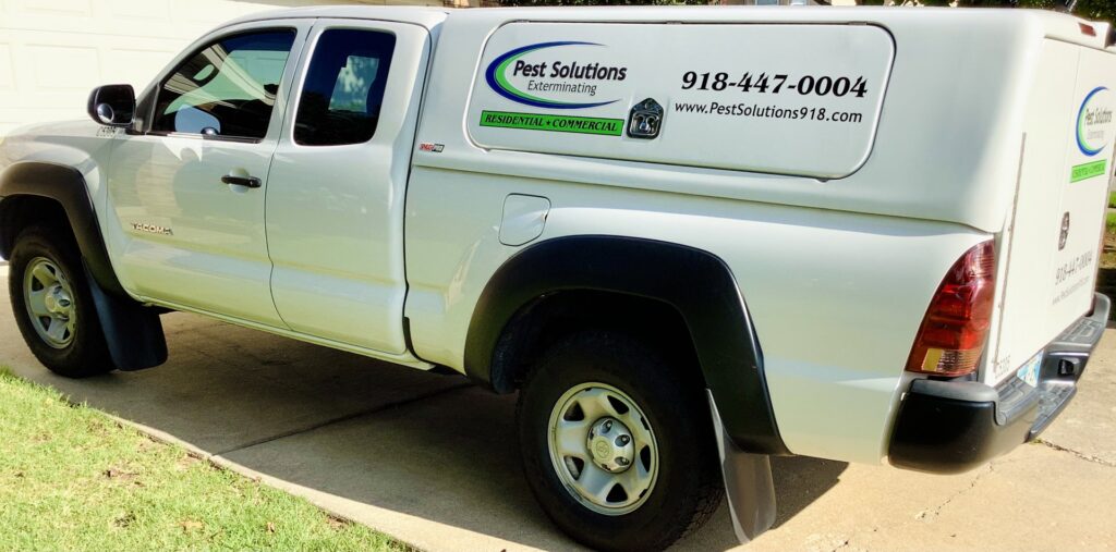 A white Pest Solutions Exterminating branded pickup truck parked on a driveway in Broken Arrow, OK.