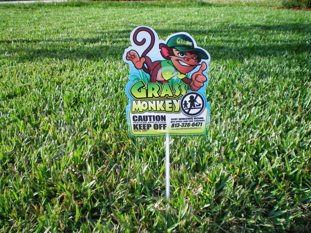 A caution sign indicating pesticide application by Grass Monkey Pest Control in a lawn in Tampa, FL.