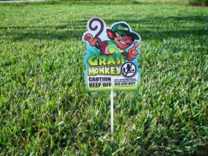 A caution sign indicating pesticide application by Grass Monkey Pest Control in a lawn in Tampa, FL.