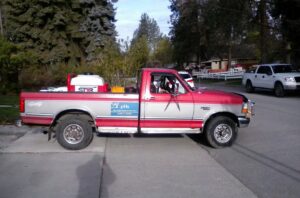 A PHS Weed & Pest Control red service truck equipped with a sprayer for pest control in Spokane, WA.