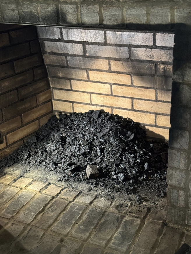 A large pile of soot and ash inside a fireplace, indicating the need for a chimney sweep by Soot Masters Chimney Service LLC in Jackson, MS.
