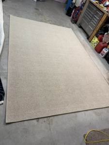 A plain beige area rug with a clearly finished edge, completed by Rug Edge Binding Company in Spokane, WA