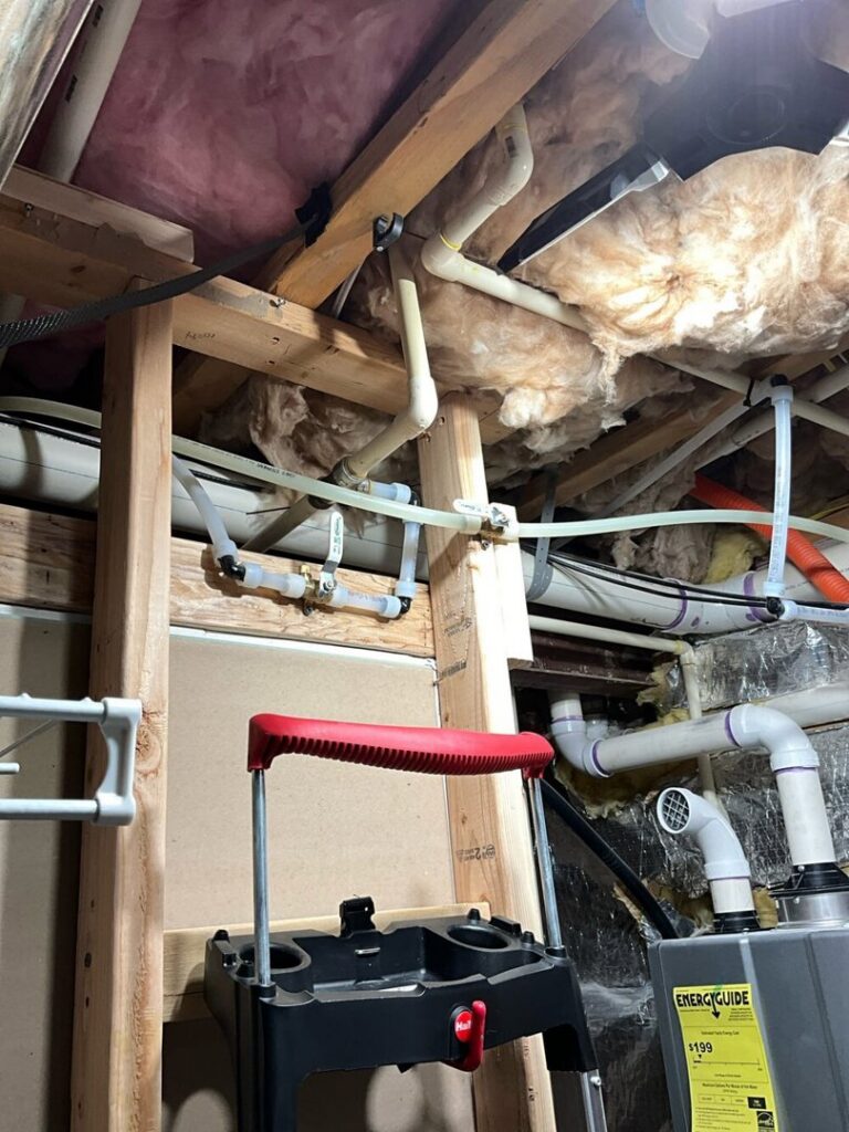 Plumbing pipes and insulation visible in a ceiling or floor joist area during a service by Markool Heating Cooling Plumbing in Frederick, MD.