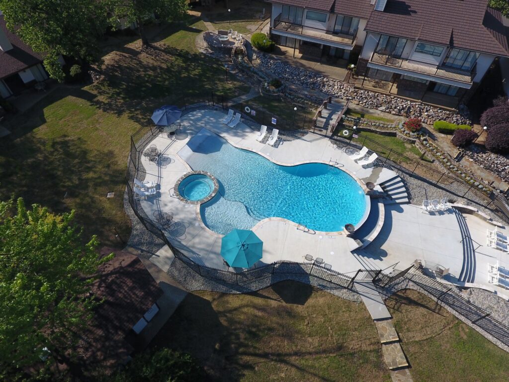 An aerial view of a swimming pool area with a newly installed black metal fence by Backyards of Little Rock, LLC in Little Rock, AR.
