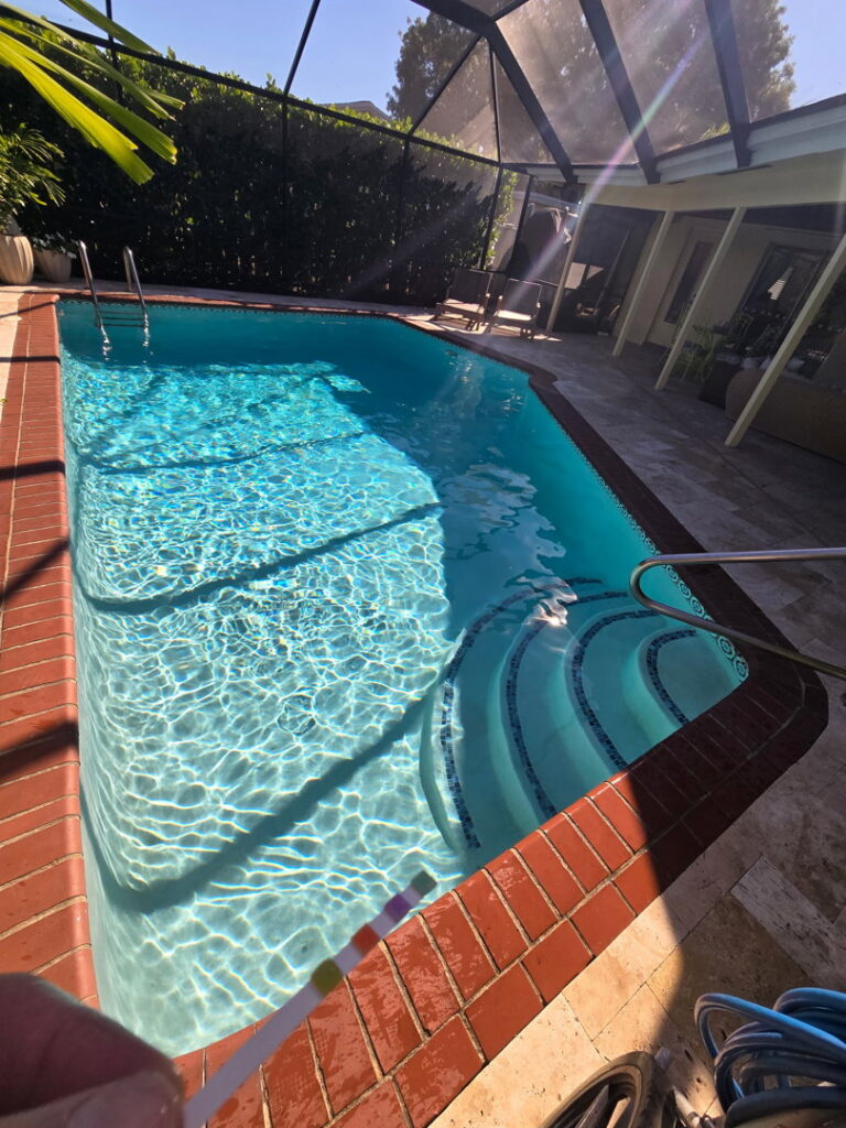 A pool brush and hose ready for cleaning a sparkling swimming pool by Summer Breeze Pool Services in Fayetteville, GA.