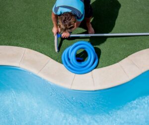 A pool cleaner from The Good Pool Company assembling a brush onto a pole next to a pool in Scottsdale, AZ.