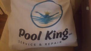 A professional pool cleaner at work, skimming a pool for Pool King in Southhold, NY.
