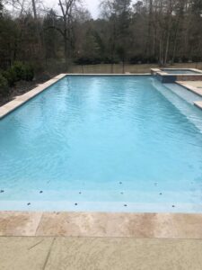 A pool cleaner brushing a cloudy swimming pool, providing service by Four Seasons Pool Services in Shreveport, LA.