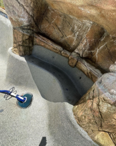 A robotic pool cleaner working in a clean, well-maintained pool by Prime Pool Care in Satellite Beach, FL.