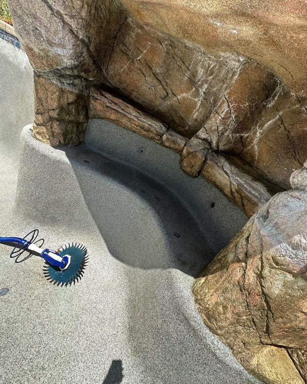 A robotic pool cleaner working in a clean, well-maintained pool by Prime Pool Care in Satellite Beach, FL.