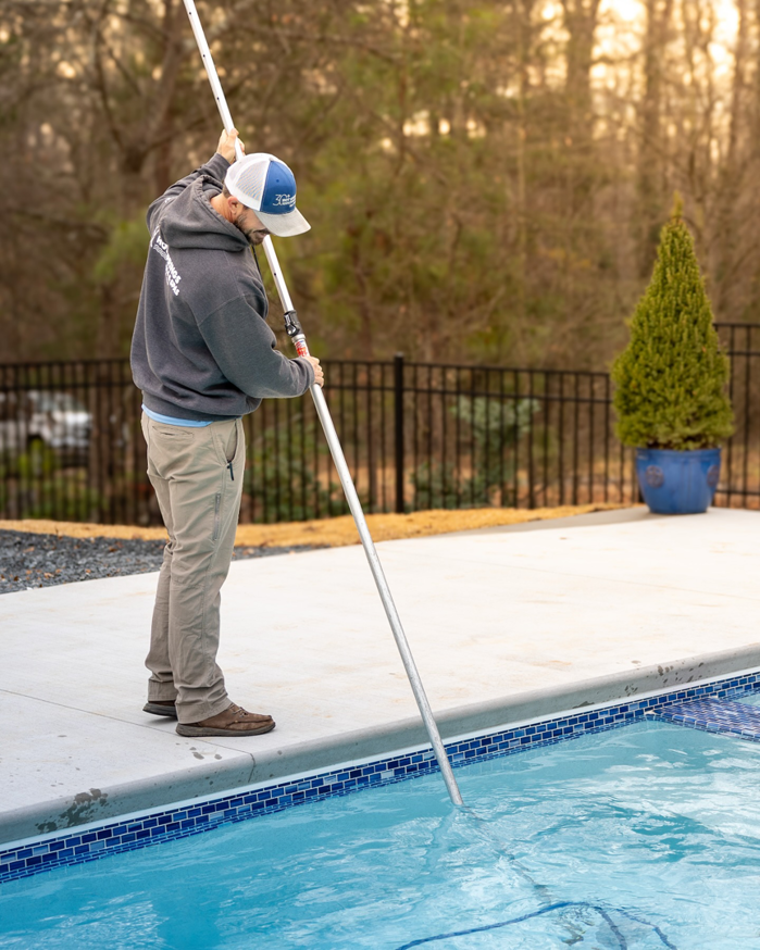 A pool cleaner skimming a residential swimming pool for Hot Springs Pool Service in Chula Vista, CA.