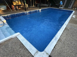 A pool cleaner from Gayle Force Pools skimming a residential swimming pool with a long pole in Lake Charles, LA