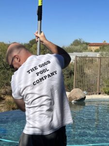 A pool cleaner from The Good Pool Company using a long pole to clean the pool in Scottsdale, AZ.