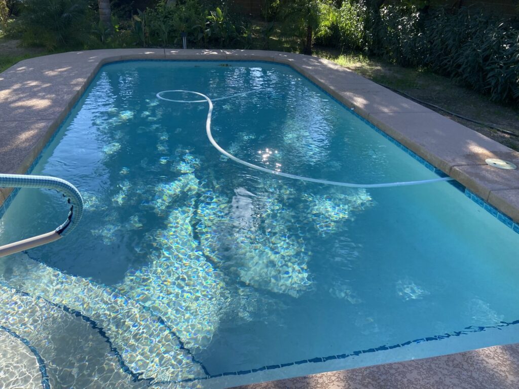 A swimming pool being cleaned with a vacuum hose by Urban Oasis Pool & Spa in Scottsdale, AZ.