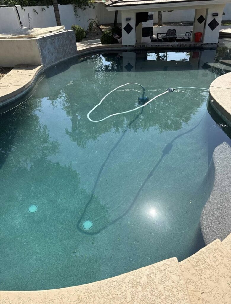 A swimming pool with a cleaning hose actively working, showing pool cleaning in progress by Pool Pals in Franklin, MA.