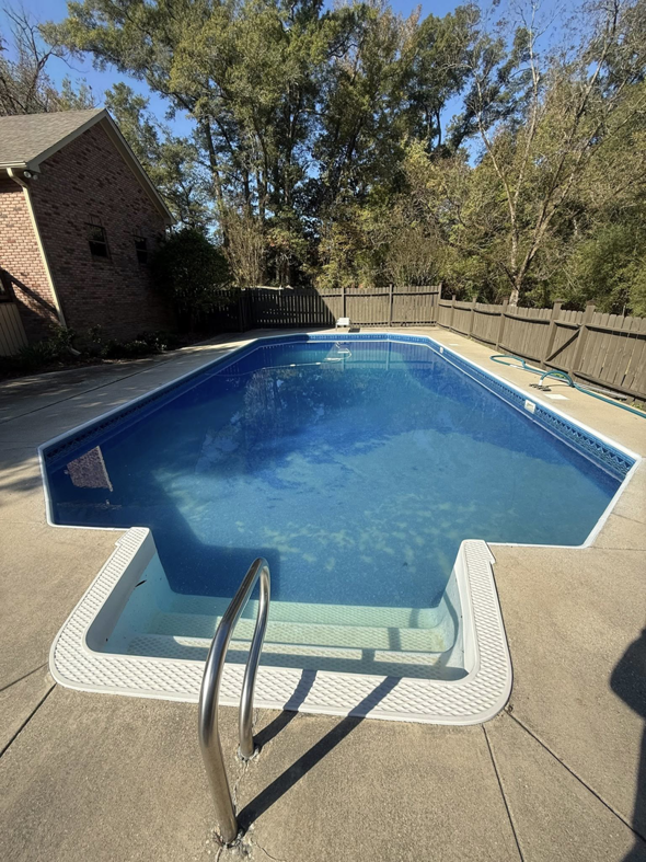 A swimming pool with a vacuum hose, showing pool cleaning in progress by KS Pool Co. LLC in Auburn, AL.