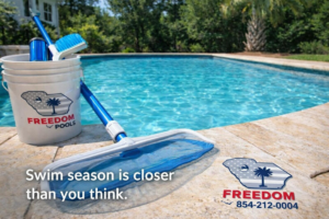 Pool cleaning tools including a skimmer net and brush by a sparkling pool from Freedom Pools in Austin, TX.