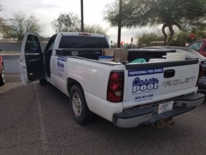 Various pool cleaning tools and supplies laid out next to a clean pool by Classic Pool Service in Surprise, AZ