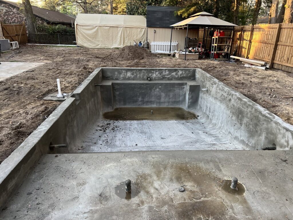 A swimming pool under construction, showing the concrete shell and excavation work by Salty Reef Pools LLC in Summerville, SC.