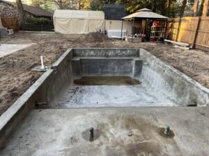 A swimming pool under construction, showing the concrete shell and excavation work by Salty Reef Pools LLC in Summerville, SC.