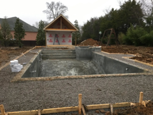 A residential pool construction site with a concrete shell and gravel base by Top Tier Pools in Franklin, TN.