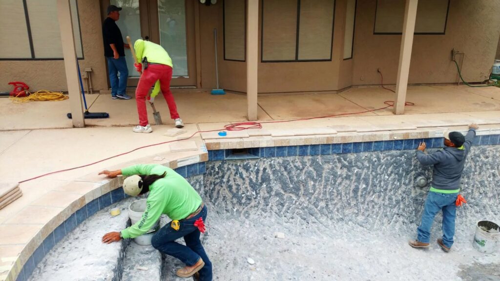 Workers installing tiling and coping during a pool construction project by Blue Magic Pools and More Inc. in Gilbert, AZ.