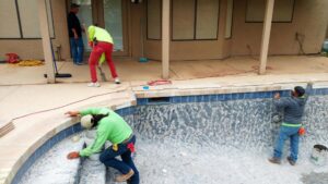 Workers installing tiling and coping during a pool construction project by Blue Magic Pools and More Inc. in Gilbert, AZ.