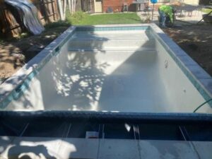 A pool under construction with a worker in the background, demonstrating the work of Wetworks Pool and Spa in Englewood, CO.