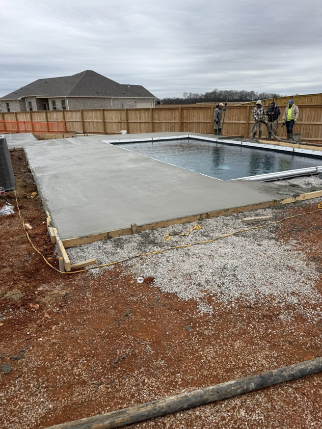 Workers pouring concrete for a new pool deck during construction by Alabama Pool Kings in Madison, AL.