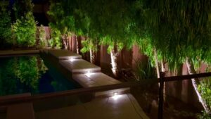 A pool deck with integrated step lighting and surrounding landscape illumination, a service by GL3 Luxury Lighting in Anaheim, CA.