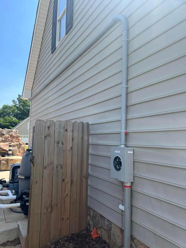 An electrical meter base and conduit installed on the exterior of a house, likely for pool equipment, by Kaufman Electric in Greensboro, NC.