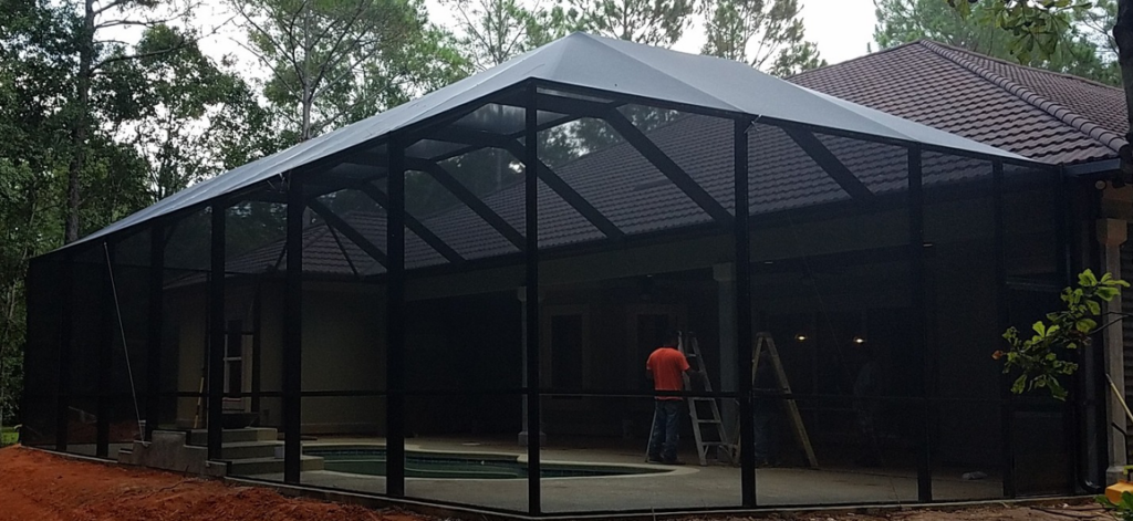 A pool enclosure under construction with a pool visible inside by Backyard Paradise in Mobile, AL.