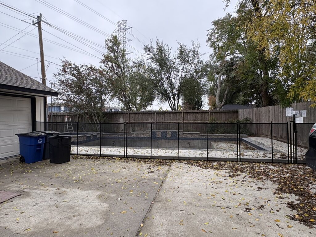 A black mesh safety fence installed around an empty swimming pool by Lone Star Pool Fence in Houston, TX.