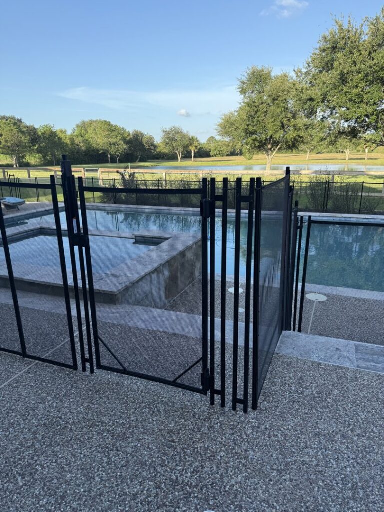 A black mesh pool fence gate installed for safety around a swimming pool by Lone Star Pool Fence in Houston, TX.