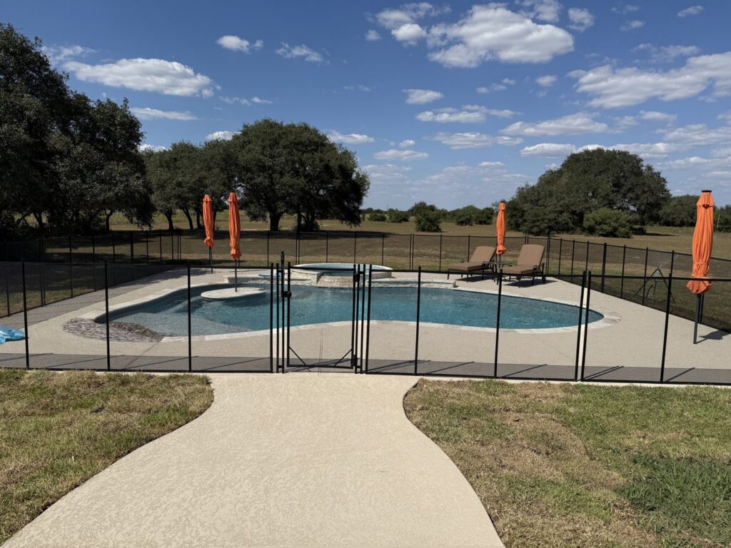 A black mesh pool fence with a self-closing gate installed for child safety by Lone Star Pool Fence in Houston, TX.