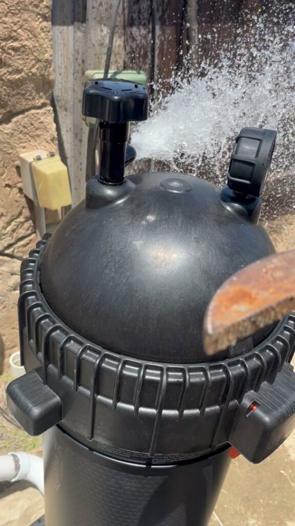 A pool filter backwashing, with water spraying out, demonstrating maintenance by Good Guy Pool Service in Moreno Valley, CA.