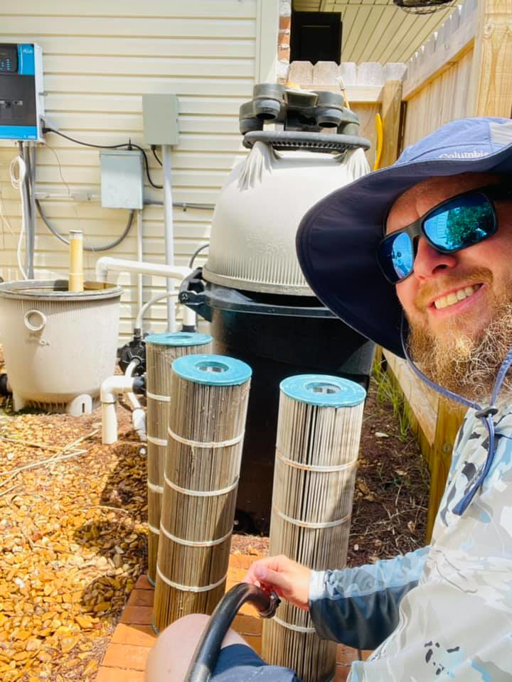 A smiling pool technician from Brocks Pools LLC with clean filter cartridges, ready for installation in Baton Rouge, LA.