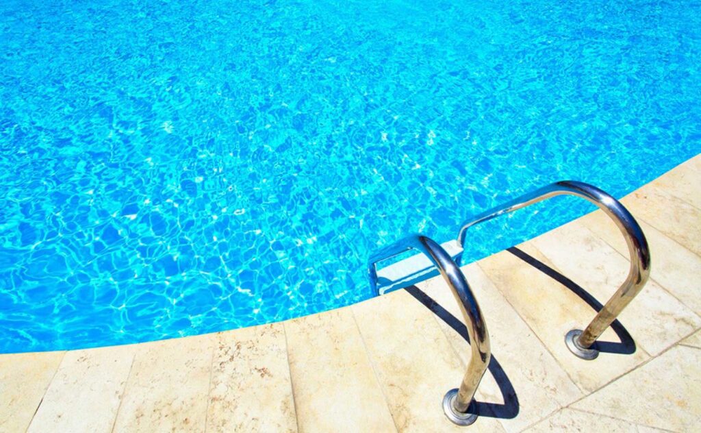 A close-up view of a pool ladder and the edge of a swimming pool by Blue Magic Pools and More Inc. in Gilbert, AZ.